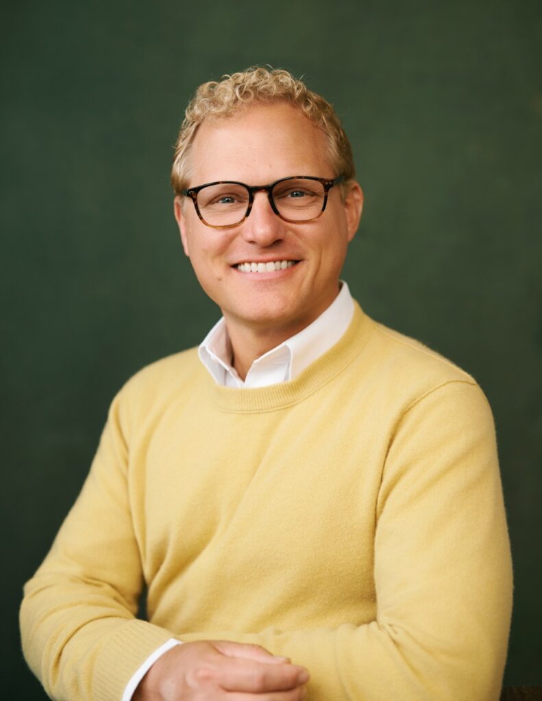 Andy Strunk headshot — Green background, yellow sweater